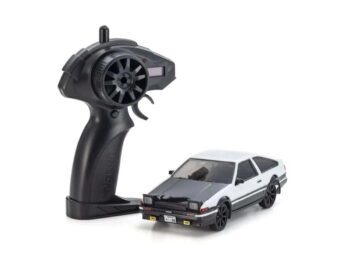 De foto toont een kleine modelauto met een afstandsbediening. De auto is wit met zwarte details en de afstandsbediening is zwart.
