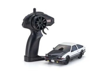 De foto toont een kleine modelauto met een zwarte afwerking op de motorkap en een witte carrosserie. Er staat ook een zwarte afstandsbediening naast de auto.