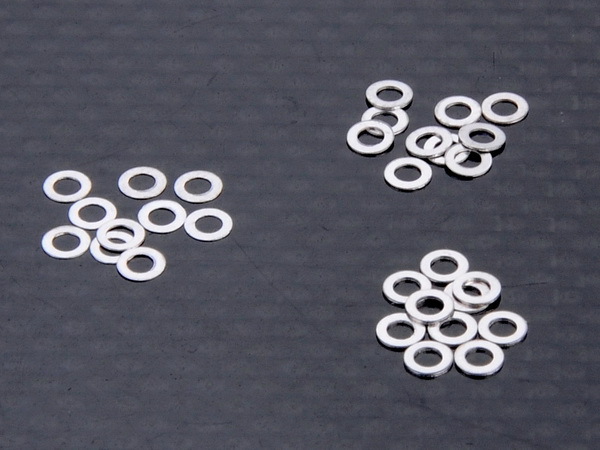 MRV-14 De afbeelding toont een verzameling kleine, platte, ringvormige metalen onderdelen. Ze hebben een zilveren afwerking en lijken op shims.