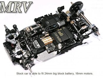 De foto toont een gedetailleerd modelauto chassis, voornamelijk zwart met zilverkleurige metalen onderdelen. Het is een achterwielaangedreven chassis met diverse elektronische componenten en mechanische onderdelen.