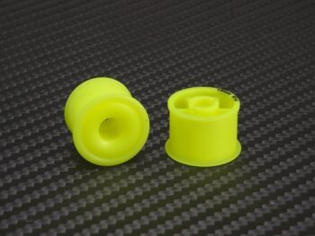 De afbeelding toont twee gele velgen van Delrin materiaal. De velgen hebben een opvallende gele kleur en een machinegesneden ontwerp, wat suggereert dat het onderdeel is voor een RC-auto.