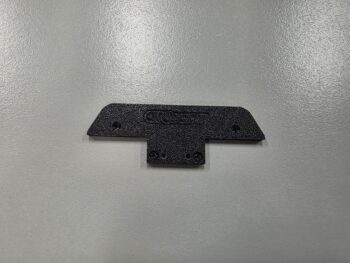 Het product is een zwart, 3D-geprint onderdeel met een getextureerd oppervlak. Er zijn gaten zichtbaar voor bevestiging.