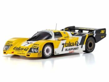 De productafbeelding toont een gele en witte raceauto met zwarte accenten en sponsorlogo's. Het is een modelauto met een aerodynamische vorm en een grote achterspoiler.