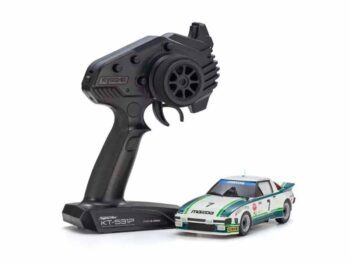 De foto toont een kleine modelauto met een bijbehorende zwarte afstandsbediening. De auto heeft een wit, groen en blauw kleurenschema met race-elementen.