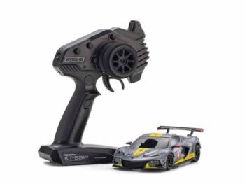 De foto toont een kleine modelauto en een afstandsbediening. De auto is grijs met gele en zwarte accenten.