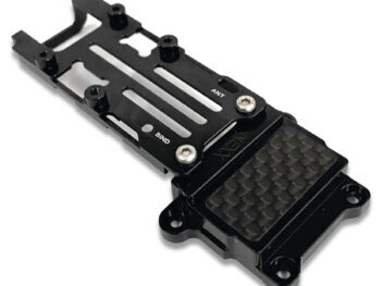 De foto toont een zwart metalen frame met een carbon fiber detail. Het frame heeft gaten voor bevestiging en de tekst 'NEXX' is zichtbaar.