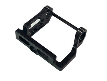 De foto toont een zwart metalen onderdeel met een rechthoekige vorm en diverse gaten en uitsparingen. Het lijkt een motor mount te zijn.