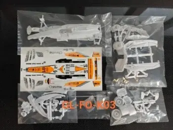 Das Foto zeigt einen Bausatz eines Formel-1-Rennwagens, bestehend aus weißen Kunststoffteilen und einem Bogen mit Aufklebern. Die Teile befinden sich in Plastiktüten.