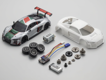 Zilveren Audi R8 RC auto met race-striping, witte body, motor, wielen, batterij, ESC en tandwielen op grijze achtergrond.