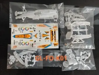 Das Foto zeigt einen Bausatz für ein Modellauto, bestehend aus weißen Kunststoffteilen und einem Bogen mit Aufklebern. Die Teile sind in Plastiktüten verpackt.