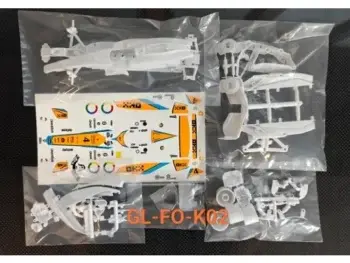 Das Foto zeigt einen Bausatz für ein Modellauto, bestehend aus verschiedenen Kunststoffteilen und einem Bogen mit Aufklebern. Die Teile sind in Plastiktüten verpackt.