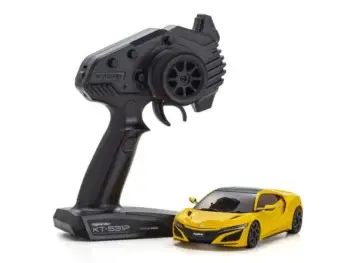 De foto toont een gele modelauto met een zwarte afwerking en een zwarte afstandsbediening. De auto heeft de vorm van een sportwagen.